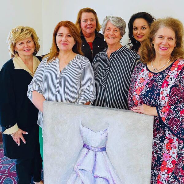 Art council members and an artist surround a painting of a dress